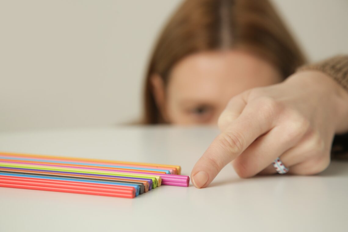 una persona con disturbo ossessivo compulsivo che sistema delle penne per metterle perfettamente allineate sopra al tavolo